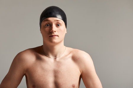 A man swimmer in goggles for swimming in full growth on a gray background, preparing an athlete for a swim, copy spaceの写真素材