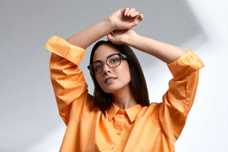 Girl in bright clothes and sunglasses, brunette, stylishly dressed, on a gray background on a gray background, advertising glasses, copies of space, close-upの写真素材
