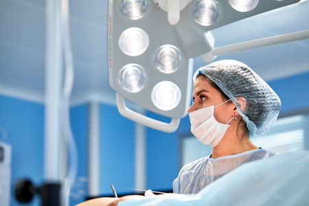 The face of a surgeon in a mask on the background of the operating room, close-up of a working...