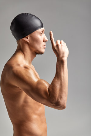 Young professional swimmer man indicates with fingers up showing a blank space.の写真素材