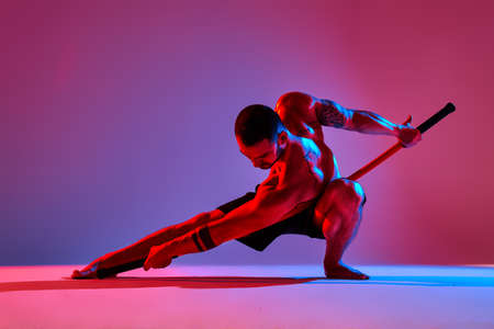 athlete men silhouette with stick training karate using sports tool in studio on colorfull lights backgroundの写真素材
