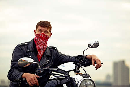 young man riding big bike ,motorcycle on city road against urban and town building sceneの写真素材