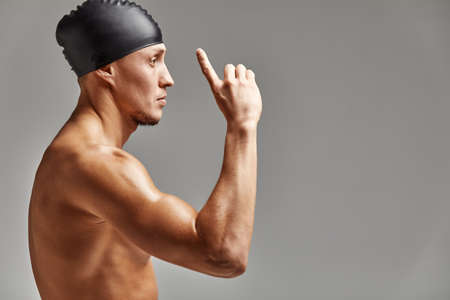 Young professional swimmer man indicates with fingers up showing a blank space.の写真素材