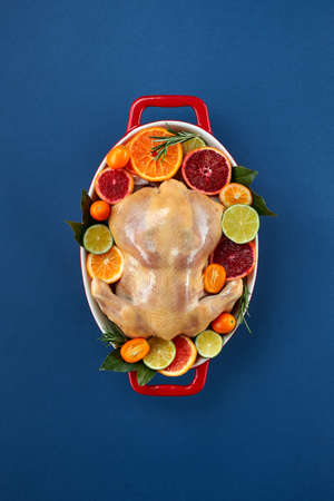 Herb and citrus oven roasted chicken. Whole chicken in roasting tin with lemon and herbs ready for the oven. Top view, blank spaceの写真素材
