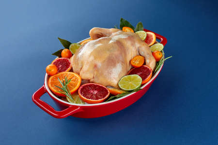 Herb and citrus oven roasted chicken. Whole chicken in roasting tin with lemon and herbs ready for the oven. Top view, blank spaceの写真素材
