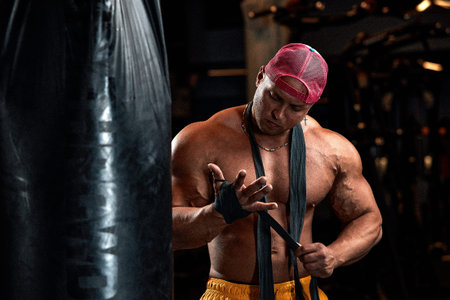Strong athletic fitness men pumping up arm muscles workout barbell curl. Fitness concept background - muscular bodybuilder men doing bodybuilding biceps exercises in gym, naked torsoの写真素材