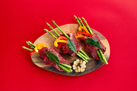 raw beef roulades and fresh vegetable trimmings ready for cooking on a white background