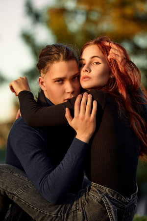 Young couple in love walking in the autumn park holding hands looking in the sunset