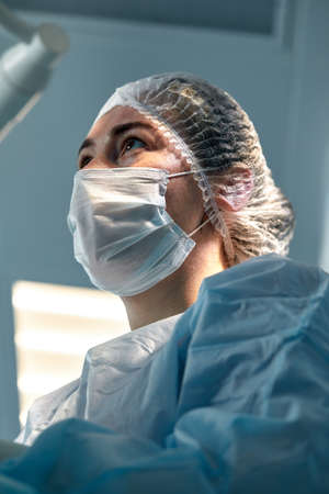 Close-up of a female surgeon in an operating room, a doctor with a tense expression on his face, in an operating room.の写真素材