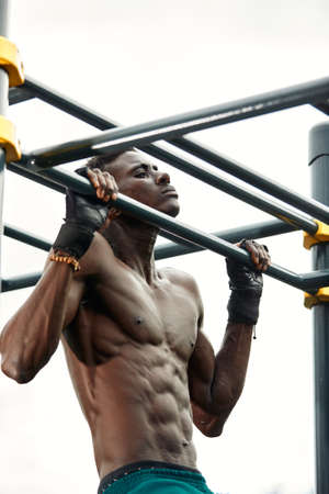 Muscular african man doing push ups in the park. Strong male athlete working out outdoors.の写真素材