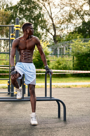 Muscular african man doing push ups in the park. Strong male athlete working out outdoors.