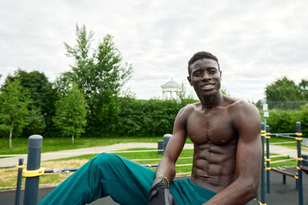 Muscular african man doing push ups in the park. Strong male athlete working out outdoors.の写真素材