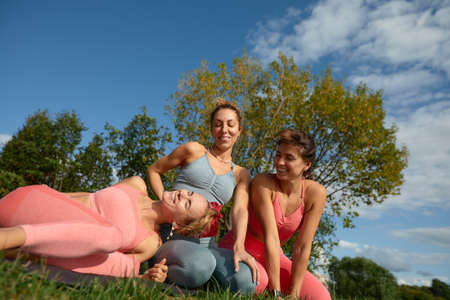 Smiling fitness women in training wear talking to each other standing on a street. Three women joggers standing on a street during their morning jogの写真素材