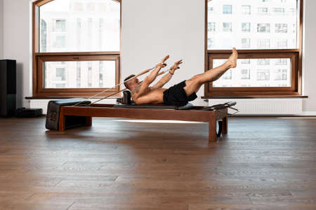 Pilates reformer workout exercises man at gym indoor.の写真素材