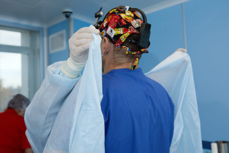 Surgeon and the nurse are preparing for surgery in the operating room. Put on gowns, hats and masks....