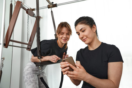 Brunette caucasian woman personal trainer during a workout session on pilates reformer bed equipment...