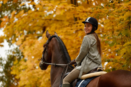 Beautiful brunette on a horse on the background of an autumn landscape. Horseback riding, active...