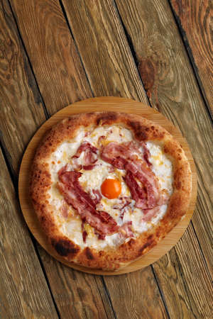 Carbonara pizza with bacon and egg on wooden backgroundの写真素材