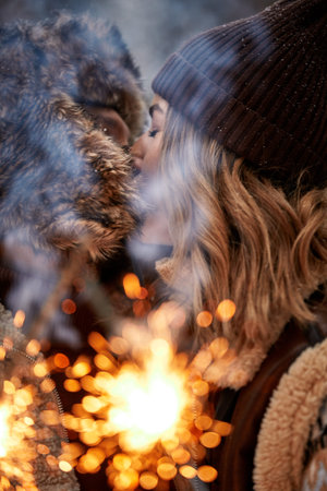Couple Love Story in Snow Forest Kissing and Holding Sparklers. Couple in Winter Nature. Couple Celebrating. Valentines day date.の写真素材