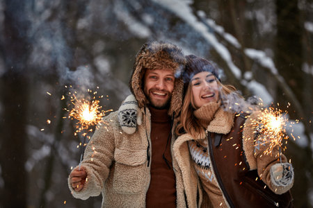 Couple Love Story in Snow Forest Kissing and Holding Sparklers. Couple in Winter Nature. Couple Celebrating. Valentines day date.の写真素材