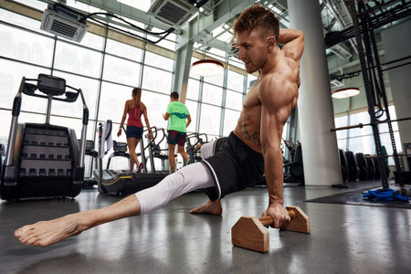 Healthy fitness man doing stretchings in the gym using wooden sports equipment. Sport concept, fat...