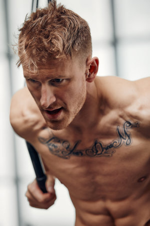 fitness, sport, bodybuilding and people concept - young man doing push-ups on gymnastic rings in gym.の写真素材