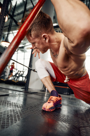 Strength concept. Male athlete using hammer during fitness workout. Fitness man beating rubber tire...