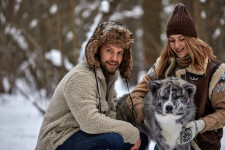 Young couple smiling and having fun in winter park with their husky dog