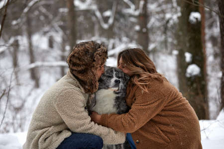 Married young couple on a walk in the winter forest with a pet dog huskyの写真素材