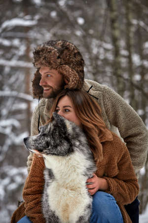 Married young couple on a walk in the winter forest with a pet dog huskyの写真素材