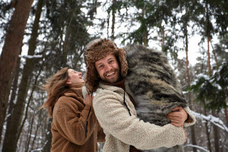Married young couple on a walk in the winter forest with a pet dog huskyの写真素材