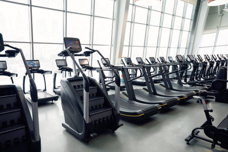 Modern gym interior with equipment. Fitness club with row of treadmills for fitness cardio training...