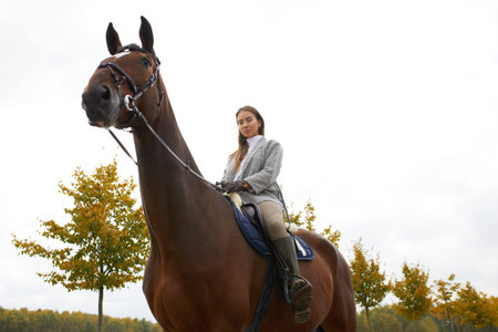 Beautiful young woman riding a horse outdoor. Concept of animal care. Rural rest and leisure. Idea...