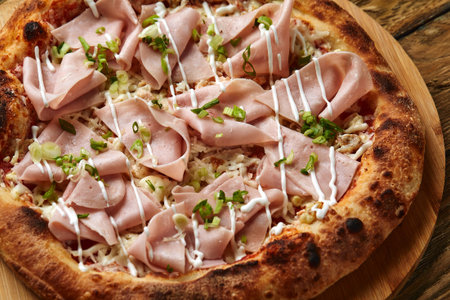 Fresh pizza with ham and pineapple on wooden table in restaurant.