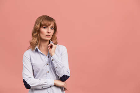 Portrait of a happy smiling mature woman with hand on chin looking at camera. Close up face of beautiful woman with fair hair on rose background. Copy spase for textの写真素材