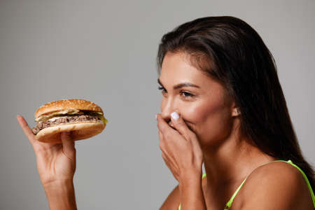 Sporty woman eating unhealthy food on light background. Diet conceptの写真素材