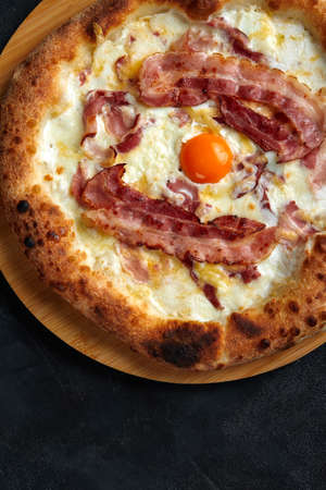Carbonara pizza with bacon and egg on dark stone backgroundの写真素材