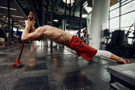 Man fitness training with large and heavy tire hits hammer. Concept workout, cross strengthの写真素材