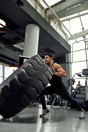 Man sitting on his toes holding a pair of battle ropes for workout. guy at the gym working out with fitness rope.の写真素材