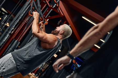 A man trains his arms and chest in the gym on the simulator, does exercises for different muscle...