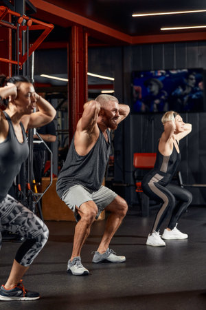 Young and active people on group sports training together do warming up and doing exercise for arm...