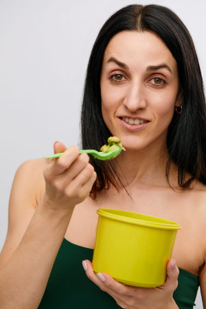 Young model healthy woman eating green vegetables avocado, cucumber and green herbs. Detoxification,...