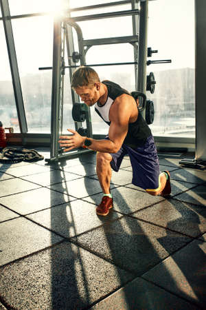 Portrait of a handsome man doing push ups exercise with modern weight equipment in fitness gym.の写真素材