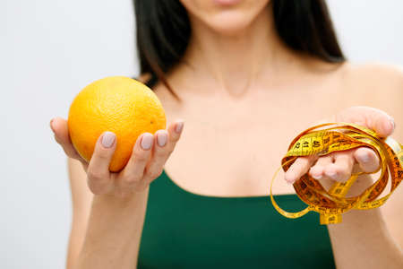 womans hand holds a centimeter-long ribbon and lemon fruit. The concept of a healthy lifestyle, natural organic food conceptの写真素材