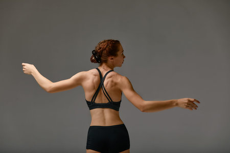 Young attractive gymnastic woman exercise, working out, wearing black sportswear, cool urban style,...