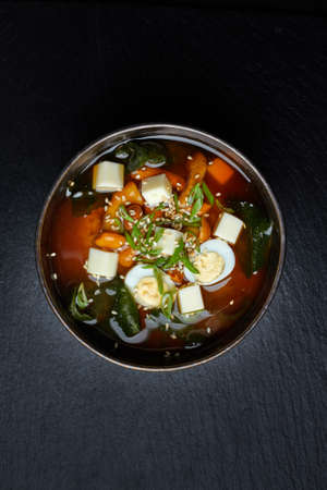 Japanese miso soup in ceramic bowl on black stone table, copy space. Asian miso soup with tofu.の写真素材