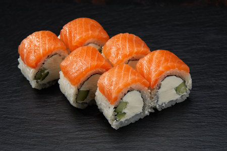 Philadelphia roll sushi with tuna, cucumber and cream cheese on black background for menu. Japanese...