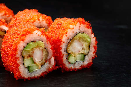 Sushi rolls california with snow crab, cream cheese, cucumber, sesame seeds and masago caviar on black background with reflection. Sushi menu, japanese kitchen.の写真素材