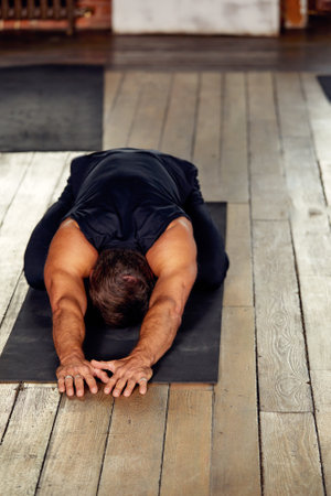 Small group of people with healthy habits doing stretching exercises on a gym floor. Selective focus on brunet womanの写真素材
