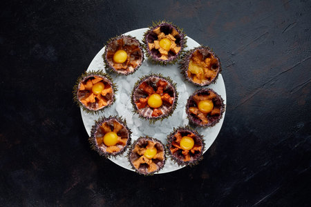 Sea urchins in a ceramic bowl with ice on. Sea urchin dish with quail egg and soy sauce.